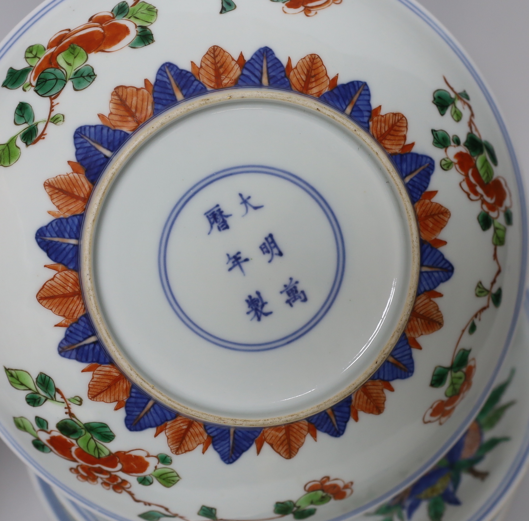 An 18th century Chinese famille rose bowl and a group of five Chinese wucai plates, each decorated with fruit, the bowl 23cm in diameter